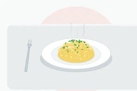 Creamy scrambled eggs in small soft glossy curds on a warm plate, scattered with freshly snipped green chives
