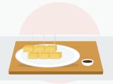 Sliced tamagoyaki showing its thin golden layers of egg, served on a plate with a small dish of soy sauce on the side